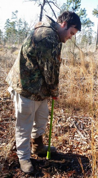 Houston Zoo staff member, Alex, using a dibbler to make holes.